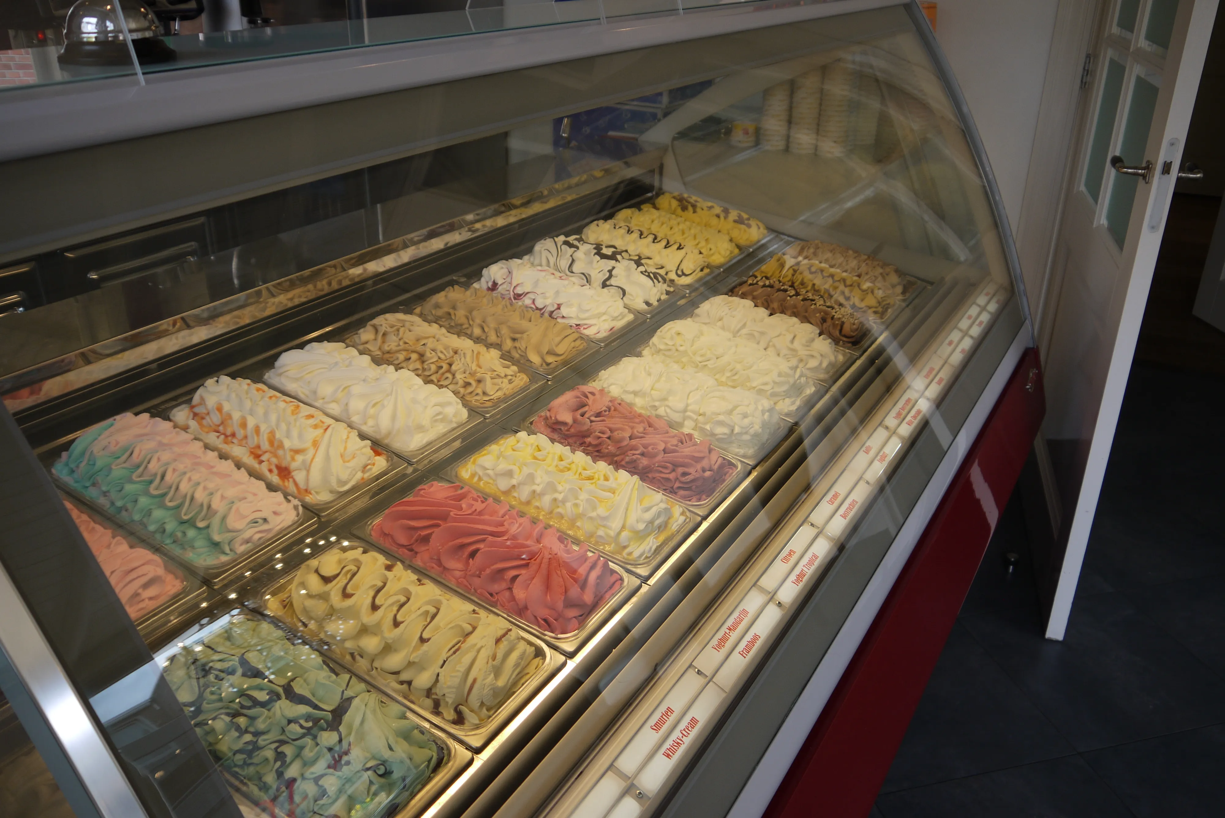 Gevulde ijsvitrine van IJssalon De Harmonie met meer dan twintig smaken schepijs